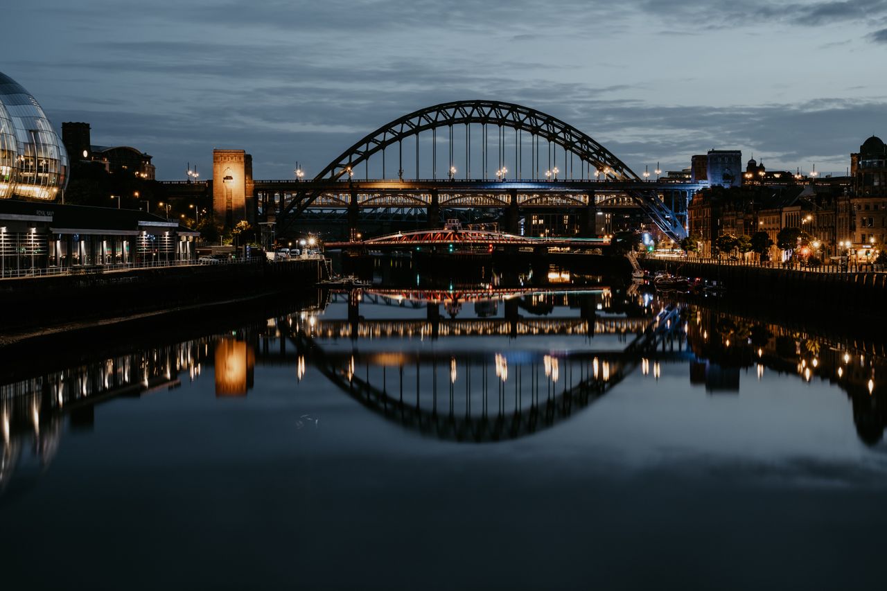 Stunning night cityscape of Newcastle's Tyne Bridge reflecting in the river.